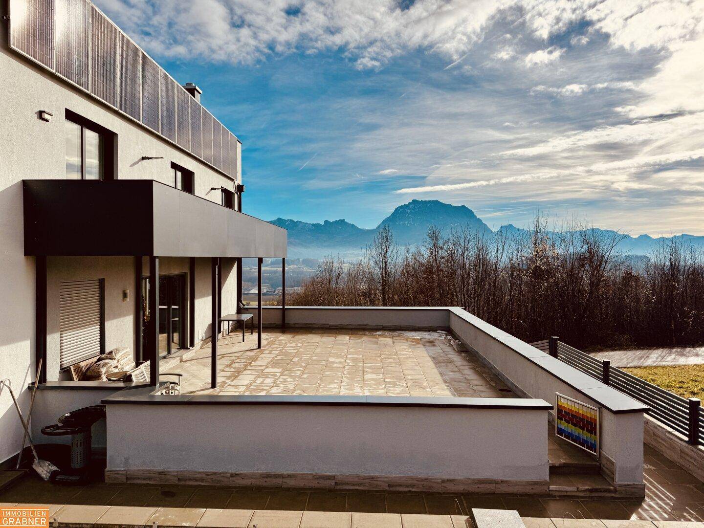 Große, sonnige Terrasse mit Fliesenboden und beeindruckendem Panoramablick auf die Berge.