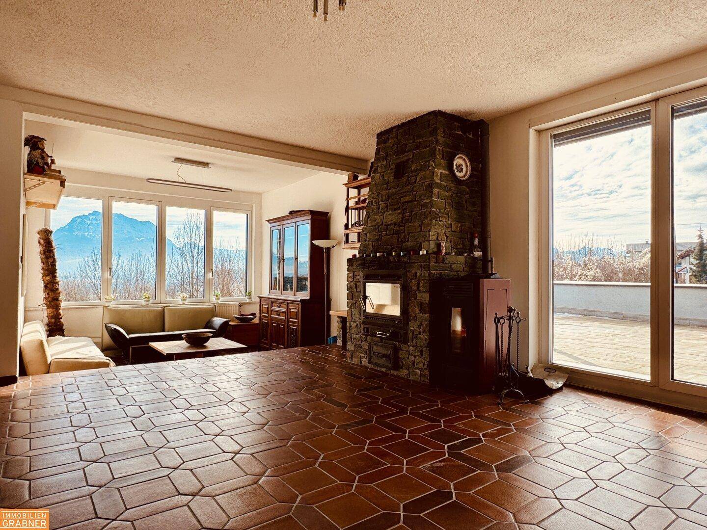 Geräumiges Wohnzimmer mit Terrakotta-Fliesenboden, großem Kamin und weitem Bergblick.