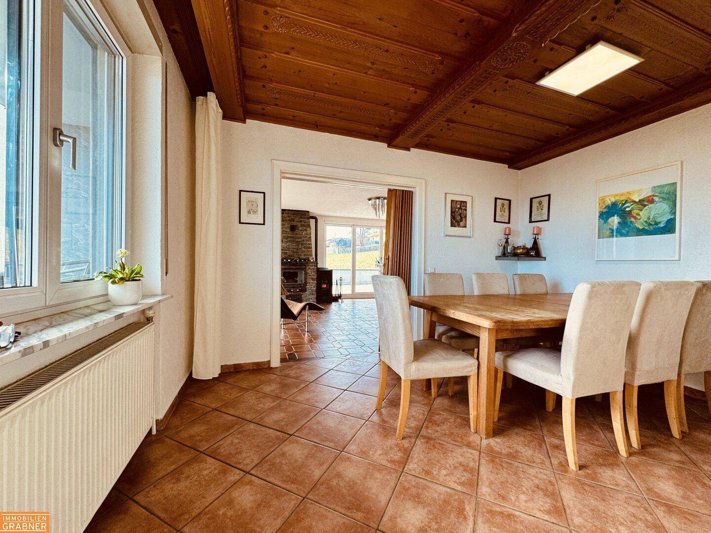 Gemütlicher Essbereich mit Holztisch, gepolsterten Stühlen und Holzbalkendecke.