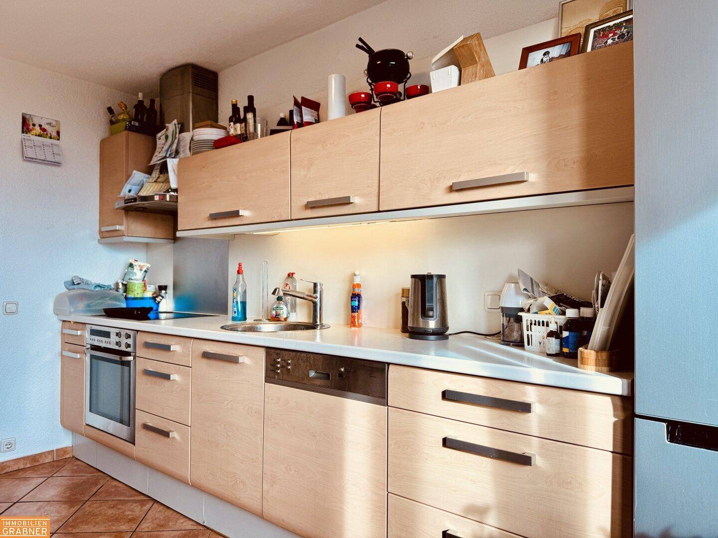 Helle Einbauküche mit Holzfronten, integrierten Geräten und ausreichend Stauraum.