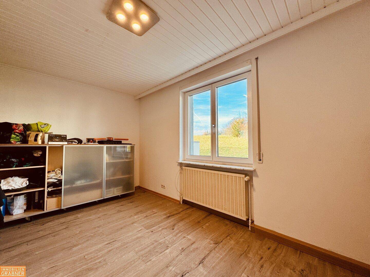 Helles Schlafzimmer mit Holzboden, großem Fenster und Blick auf die umliegende Landschaft.