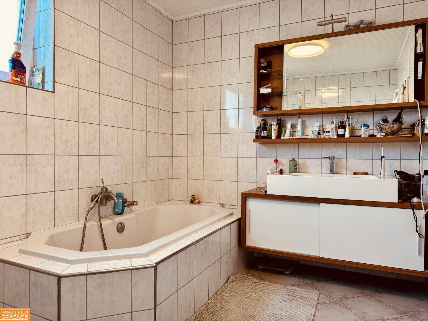 Geräumiges Badezimmer mit Eckbadewanne, Doppelwaschbecken und großem Spiegelschrank.