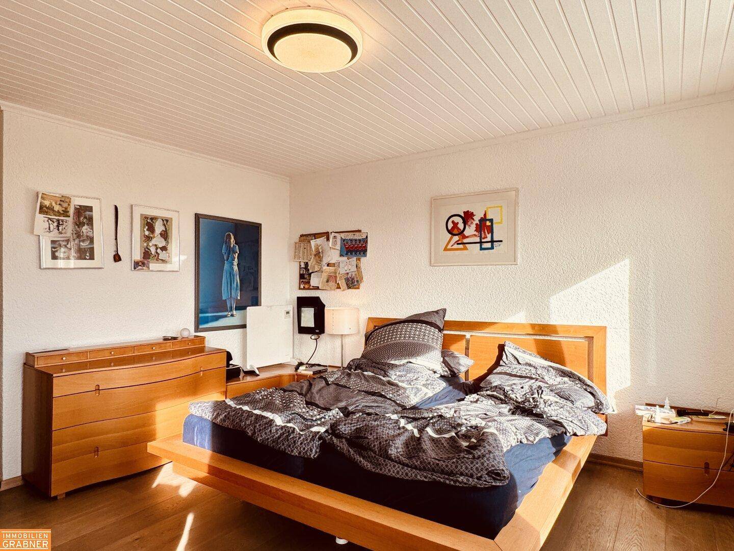 Helles Schlafzimmer mit Holzboden, Doppelbett und schlichter Einrichtung.