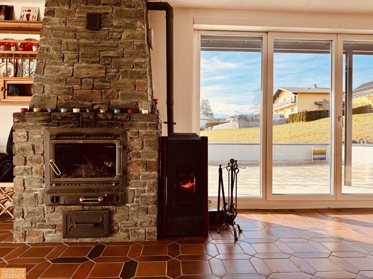 Gemütlicher Wohnbereich mit großem Steinkamin, Pelletofen und Zugang zur Terrasse.