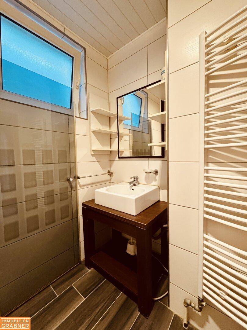 Badezimmer mit modernem Waschbecken, Spiegelschrank und Handtuchheizkörper.