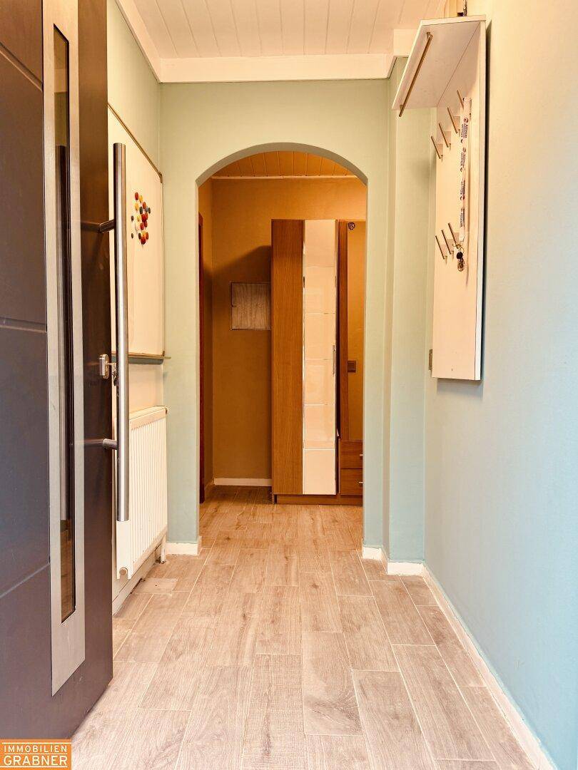 Heller Flur mit Holzboden und einem eleganten Bogendurchgang zu weiteren Räumen.