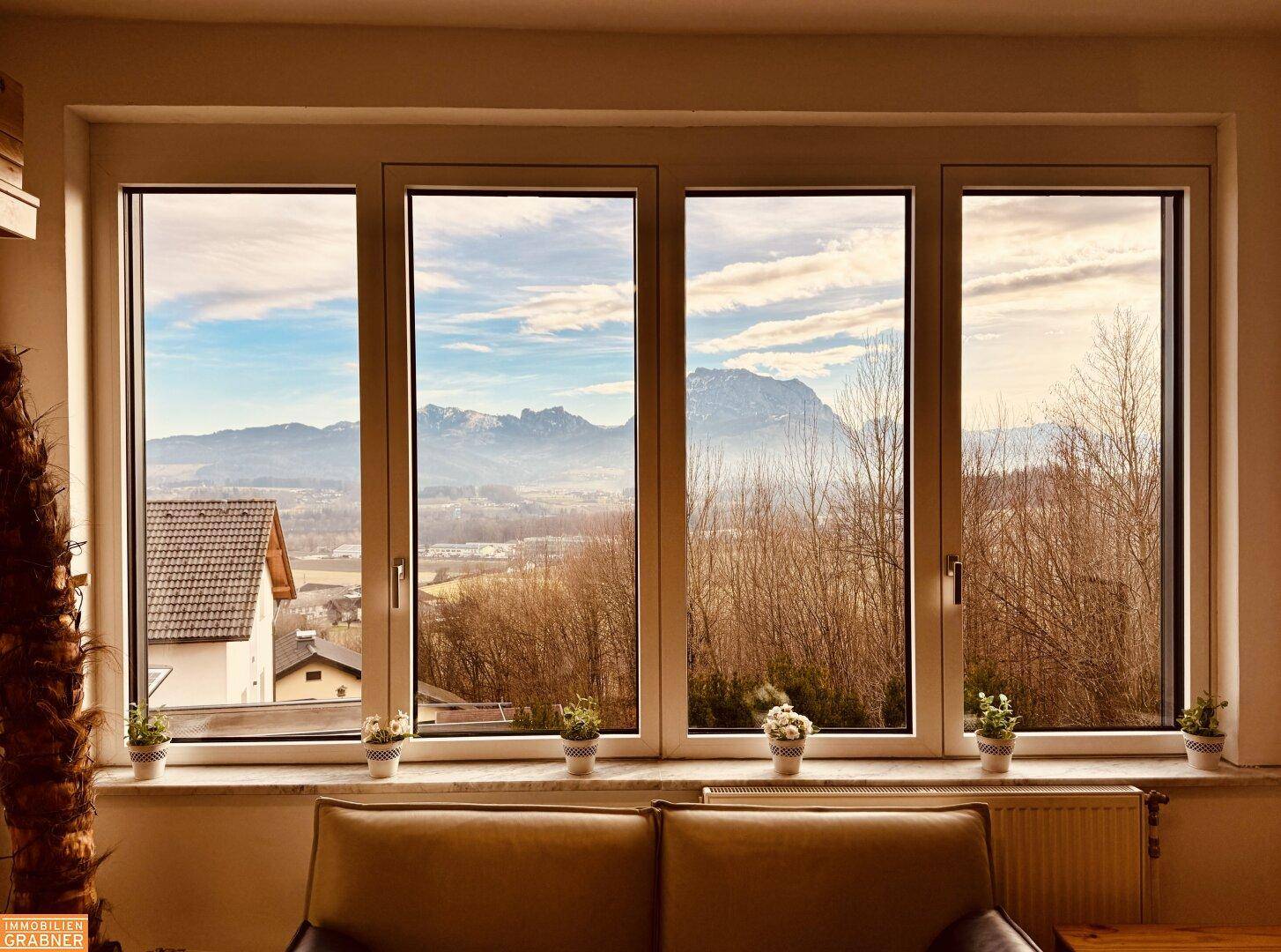 Große Fensterfront im Wohnzimmer bietet einen weiten Blick auf die Berge und Landschaft.