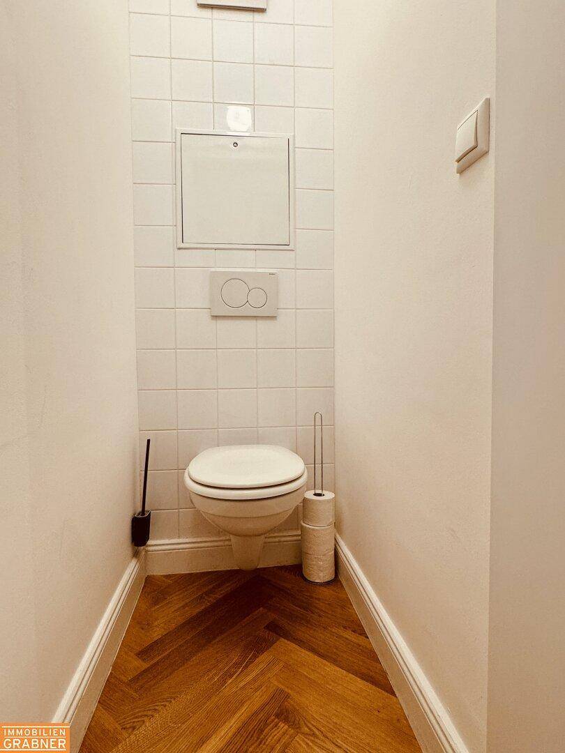 Kleines Gäste-WC mit wandhängendem WC und Fischgrätparkett.