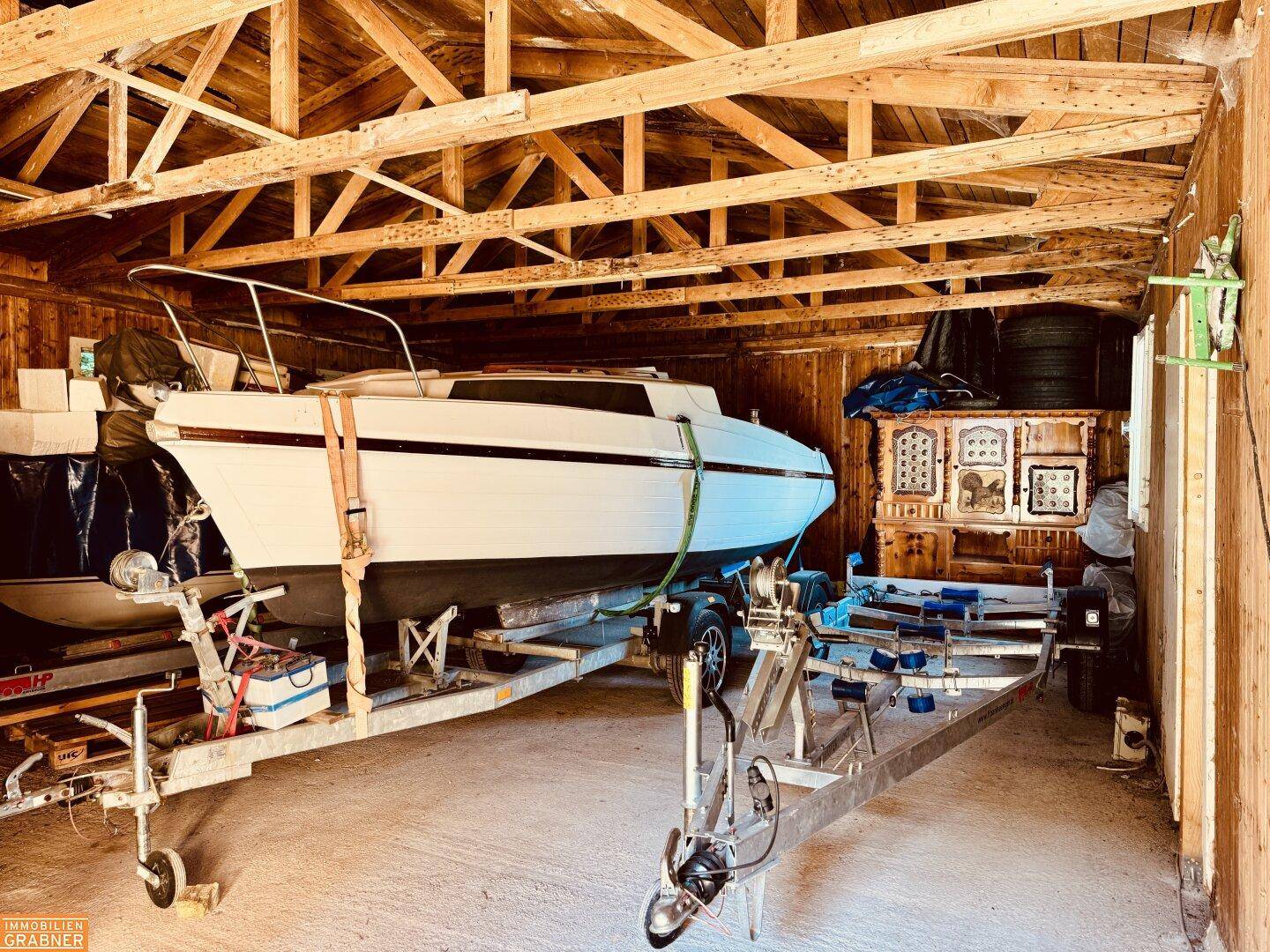 Geräumige Garage oder Lagerraum mit Holzkonstruktion und einem Boot auf einem Anhänger.