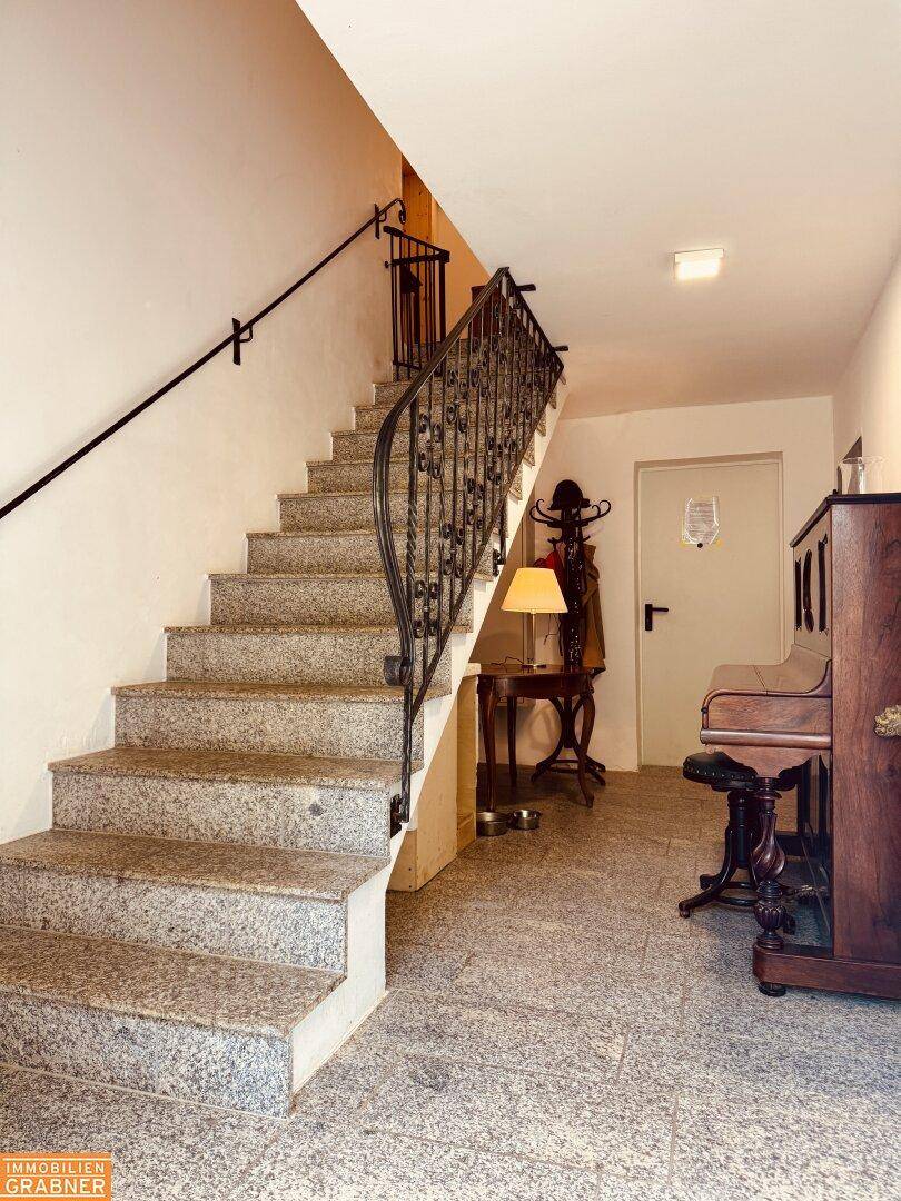 Eingangsbereich mit Granittreppe, schmiedeeisernem Geländer und traditionellen Möbeln.