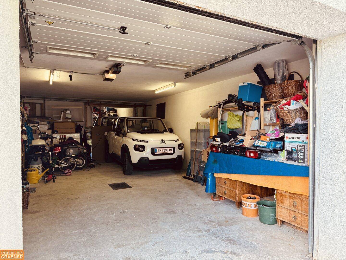 Geräumige Garage mit einem Auto und viel Stauraum für verschiedene Gegenstände.