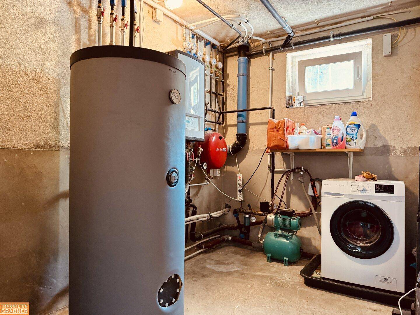 Hauswirtschaftsraum im Keller mit Waschmaschine, Warmwasserspeicher und Heizungsinstallationen.
