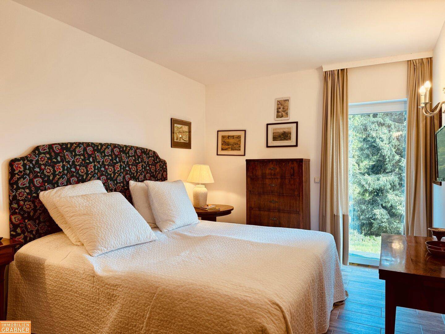 Helles Schlafzimmer mit Doppelbett, Holzboden und direktem Zugang zu einem Balkon oder Garten.