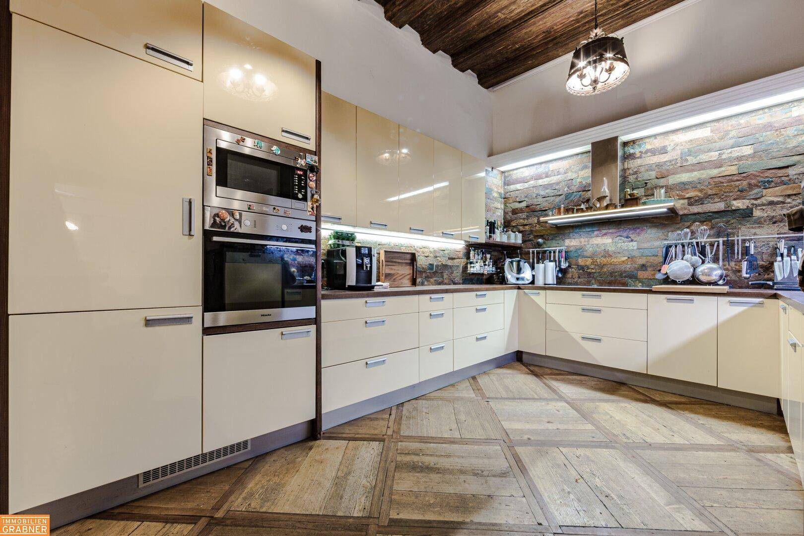 Moderne Einbauküche mit hellen Fronten, integrierten Geräten und Steinwand-Akzent.