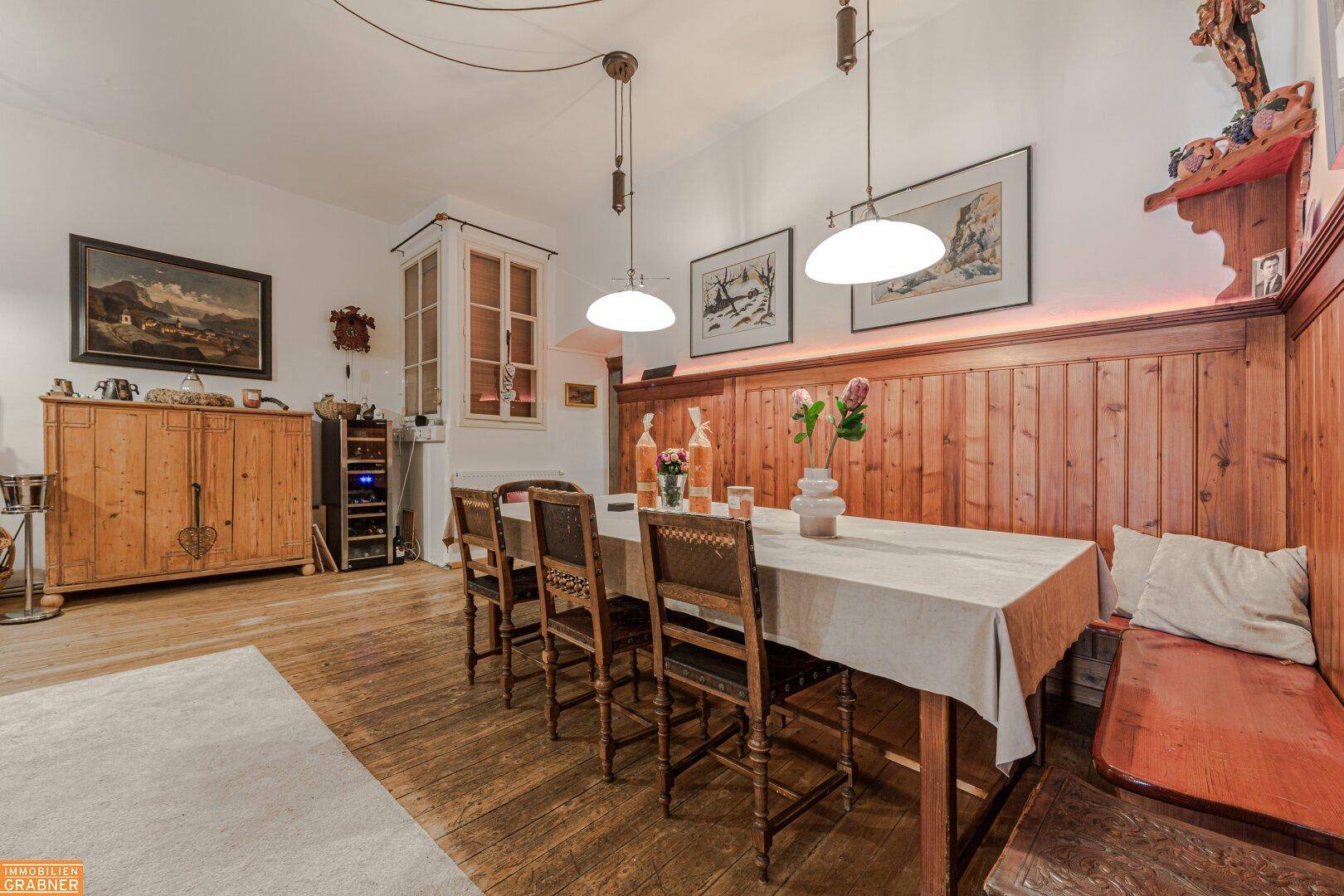 Gemütlicher Essbereich mit Holztisch, Bänken und traditioneller Holzvertäfelung an der Wand.