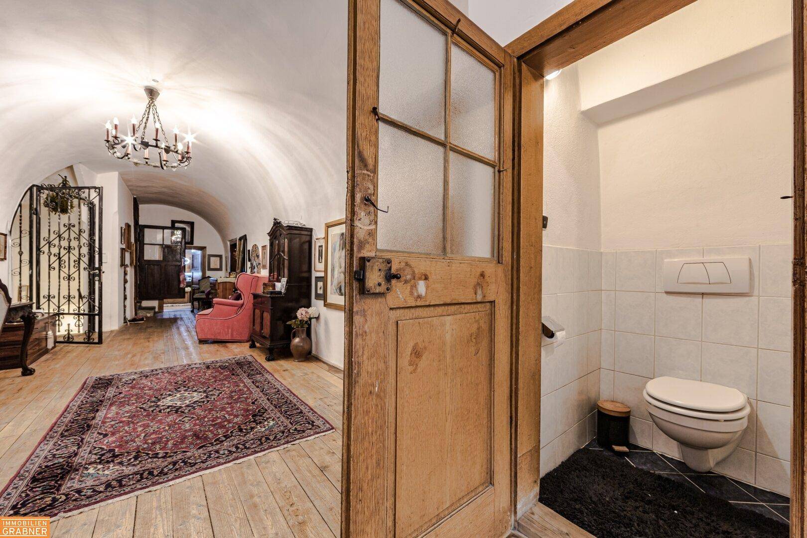 Kleines Gäste-WC mit Wand-WC und Fliesenboden, direkt vom Flur zugänglich.