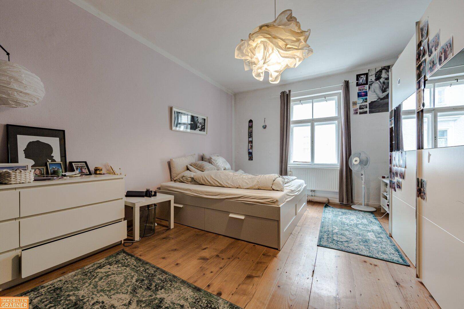 Helles Schlafzimmer mit Doppelbett, Holzfußboden und weißem Kleiderschrank.