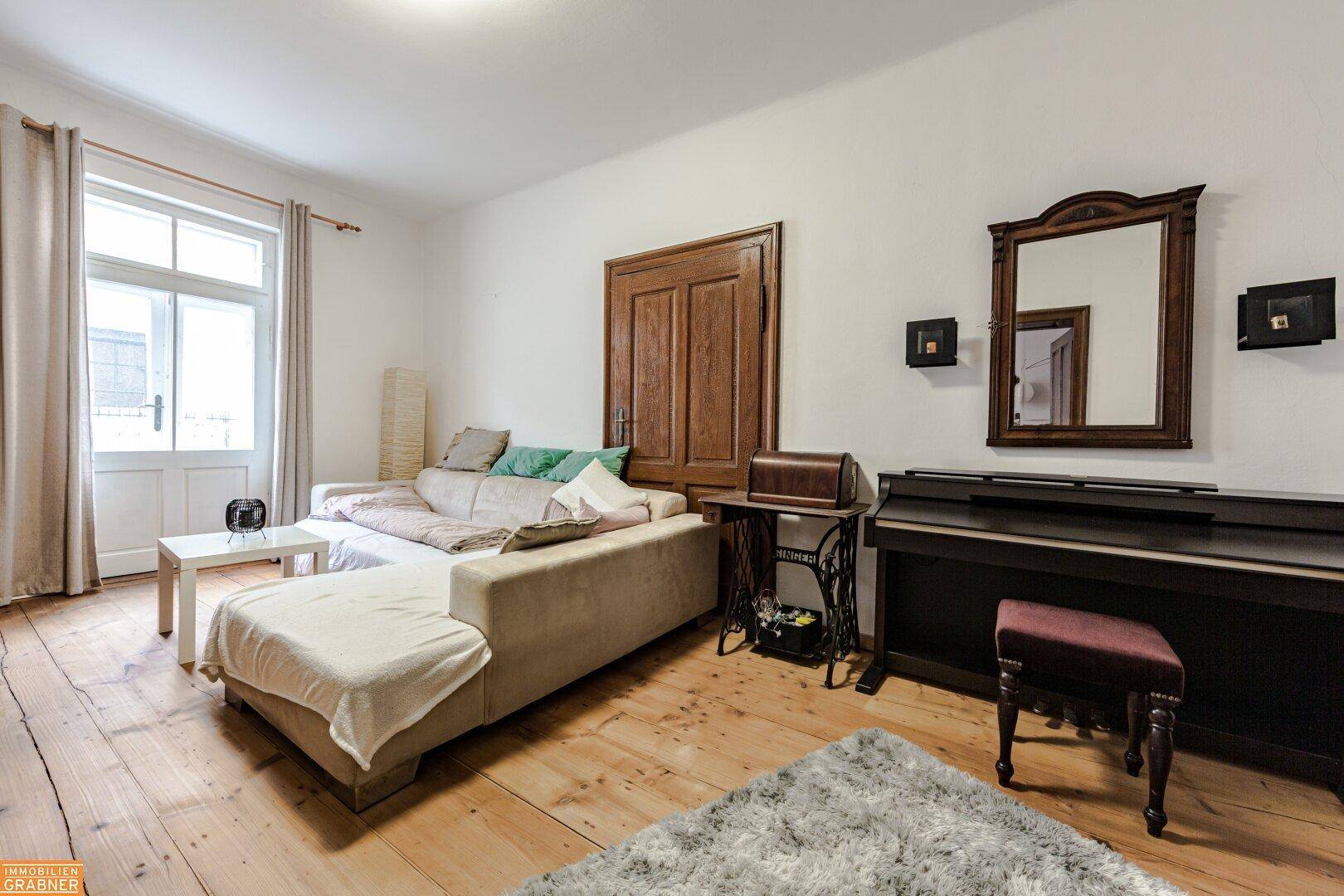 Gemütliches Wohnzimmer mit Holzboden, beigem Sofa und einem Klavier, ideal zum Entspannen.