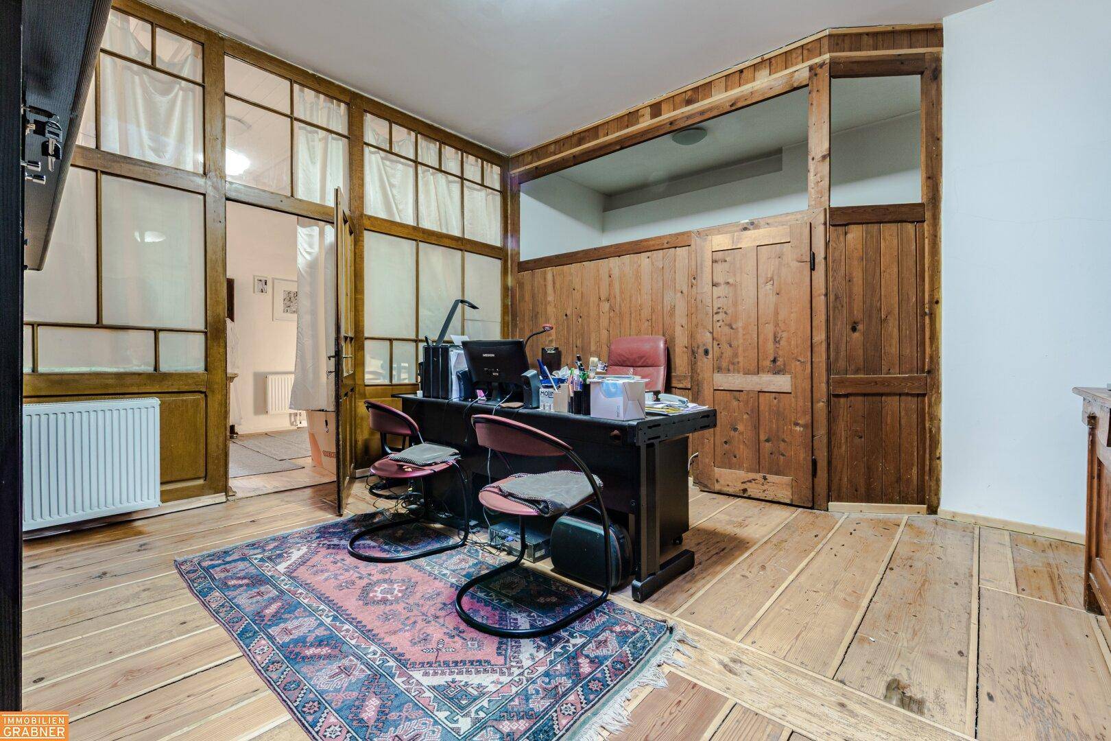 Geräumiges Arbeitszimmer mit Holzboden, Holzvertäfelung und großem Schreibtisch, bietet viel Platz.