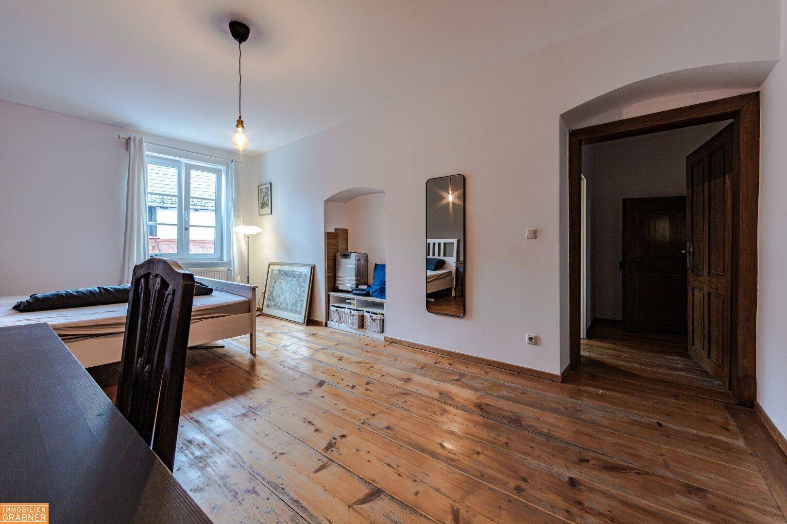 Schlafzimmer mit Holzboden, Bett und Nischen, bietet eine gemütliche und funktionale Einrichtung.