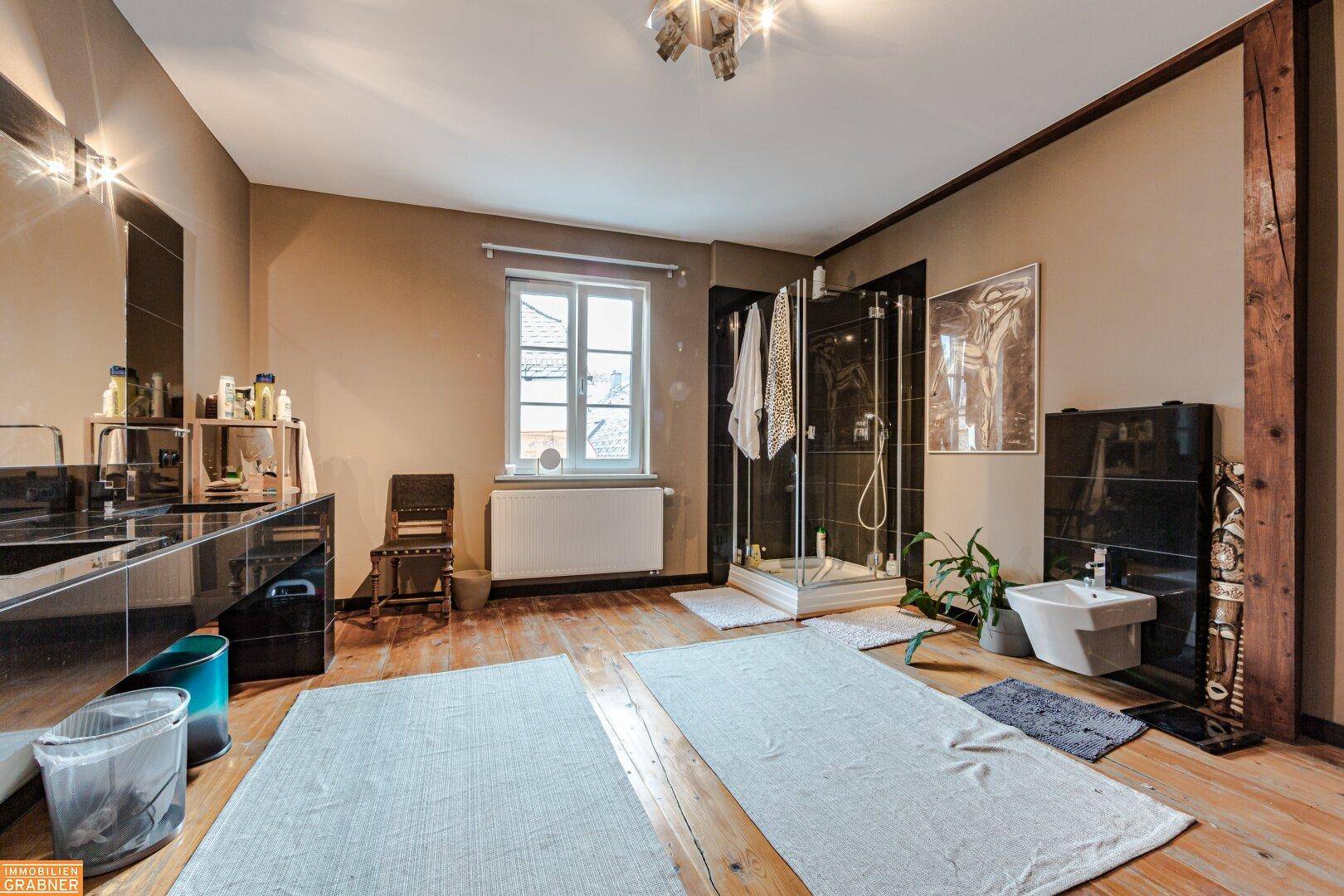 Geräumiges Badezimmer mit Holzboden, Doppelwaschbecken und Duschkabine, bietet Komfort.