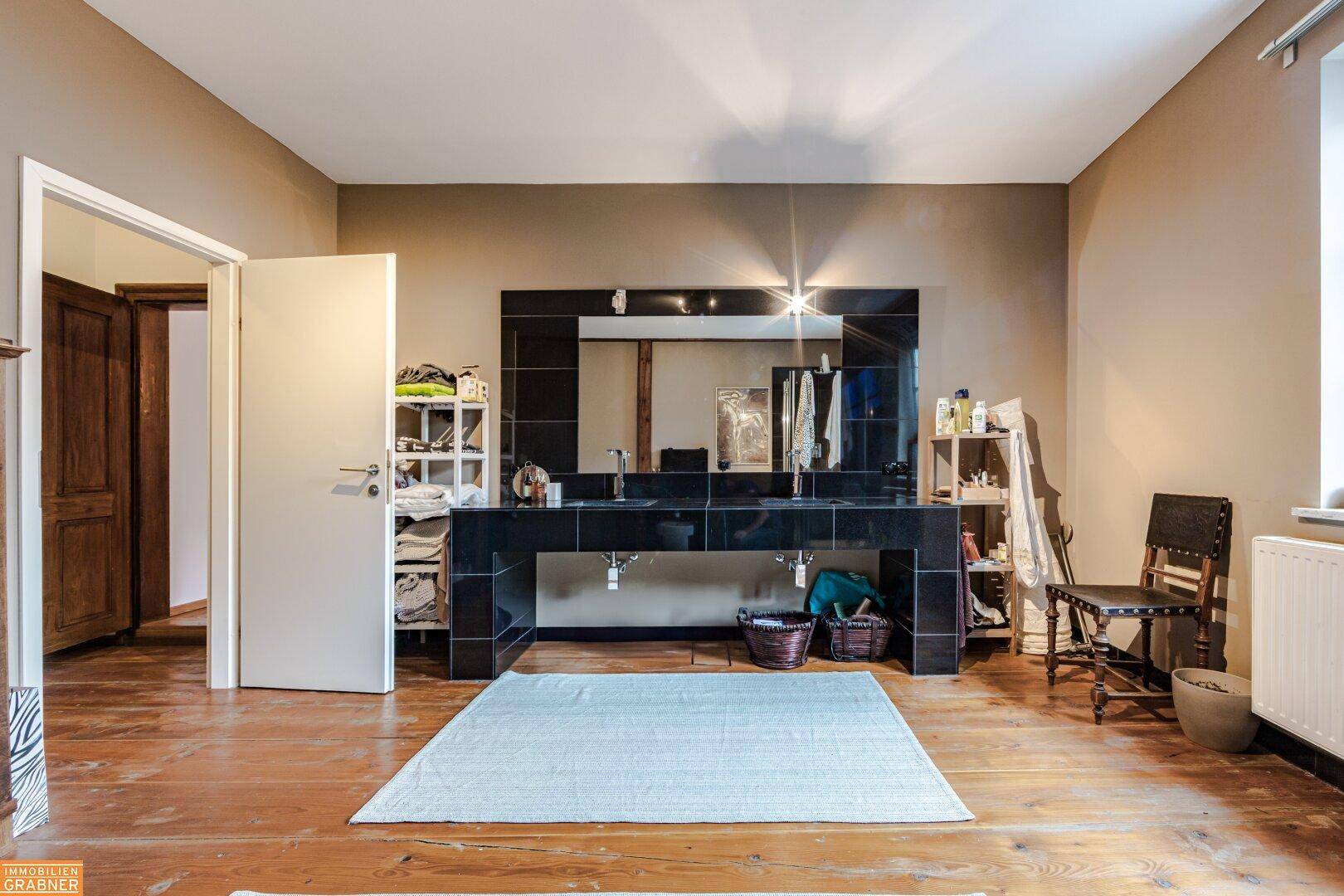 Modernes Badezimmer mit dunklem Doppelwaschbecken und großem Spiegel, stilvoll und funktional.