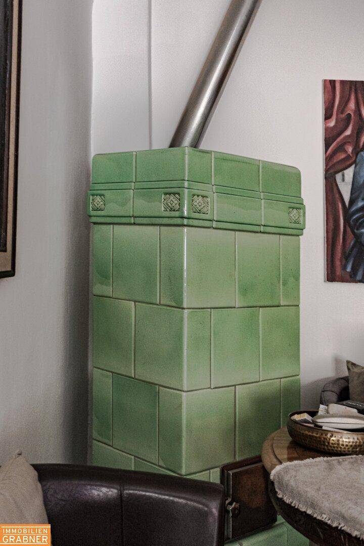 Grüner Kachelofen in einem Wohnbereich, der Wärme und traditionellen Stil verleiht.