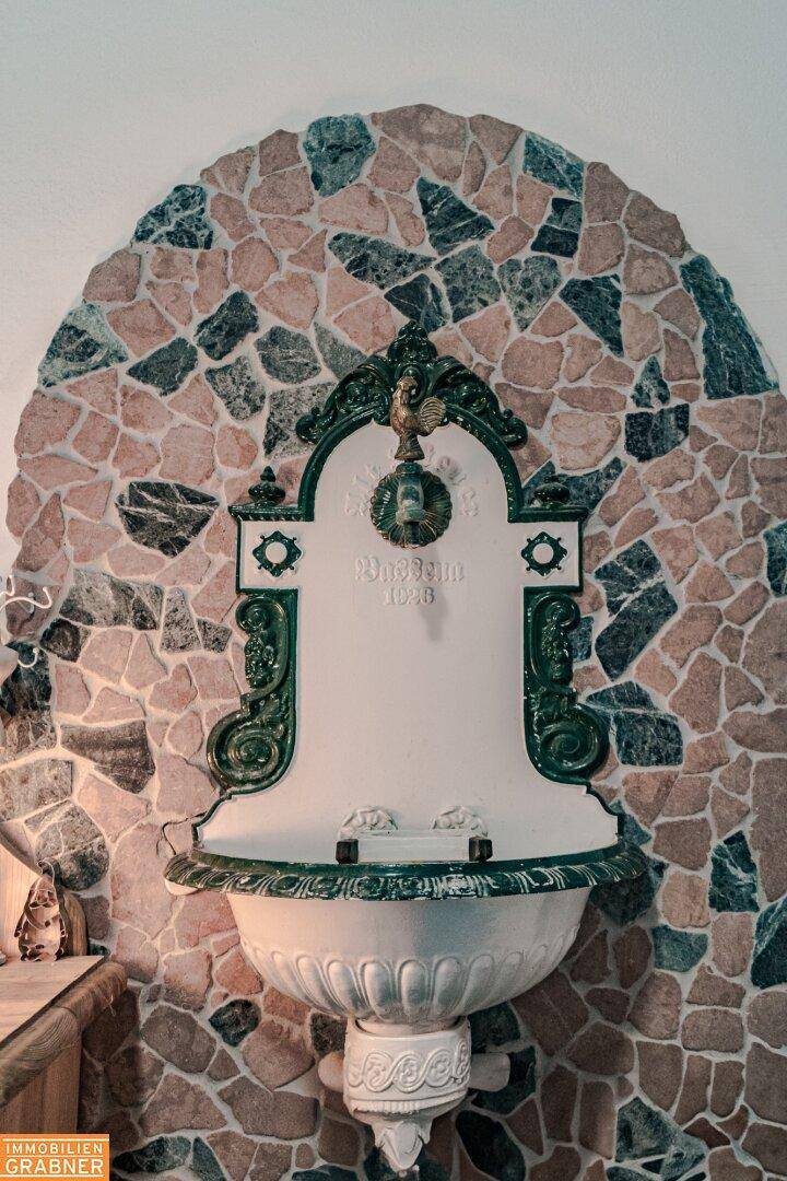 Dekorativer Wandbrunnen im Innenbereich mit aufwendigen Verzierungen und Mosaikfliesen.