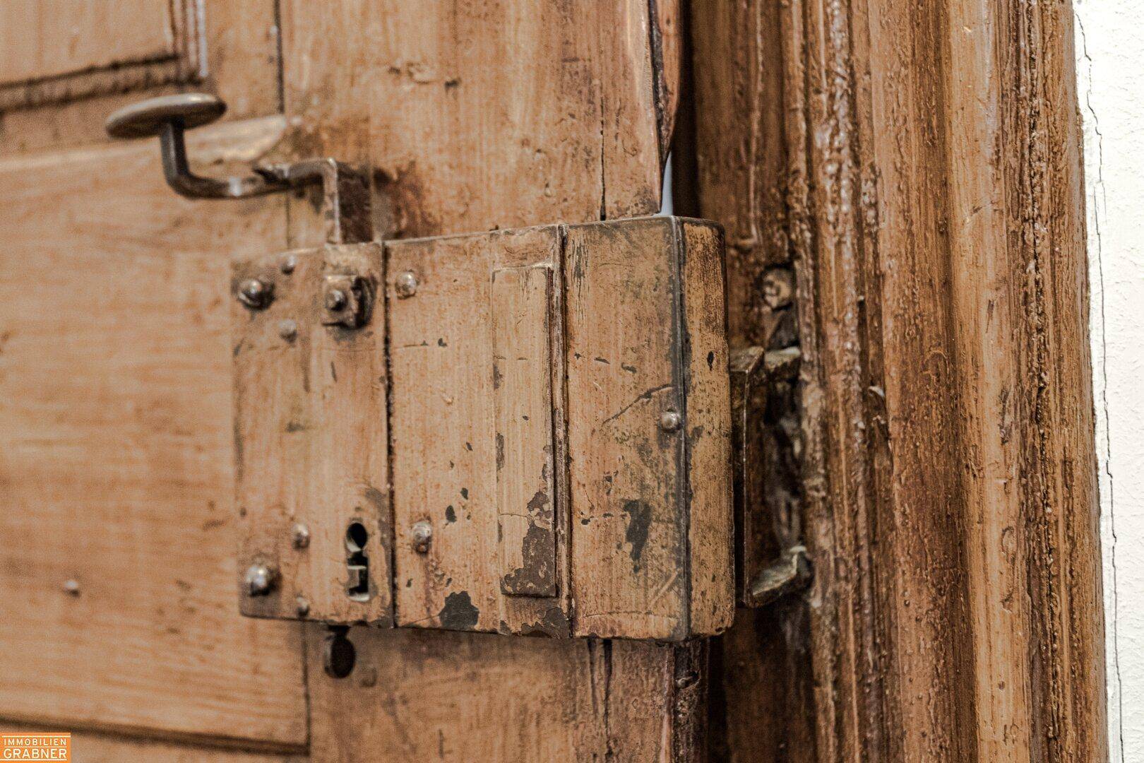 Detailansicht eines alten, verwitterten Holztürschlosses mit sichtbaren Gebrauchsspuren.