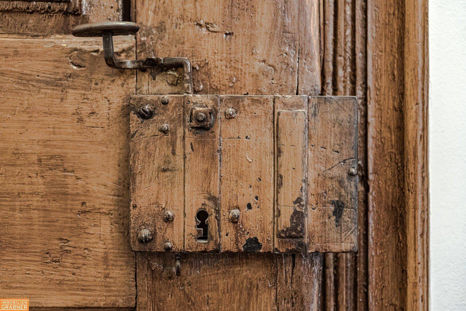 Rustikales Türschloss an einer Holztür, das den Charme vergangener Zeiten widerspiegelt.