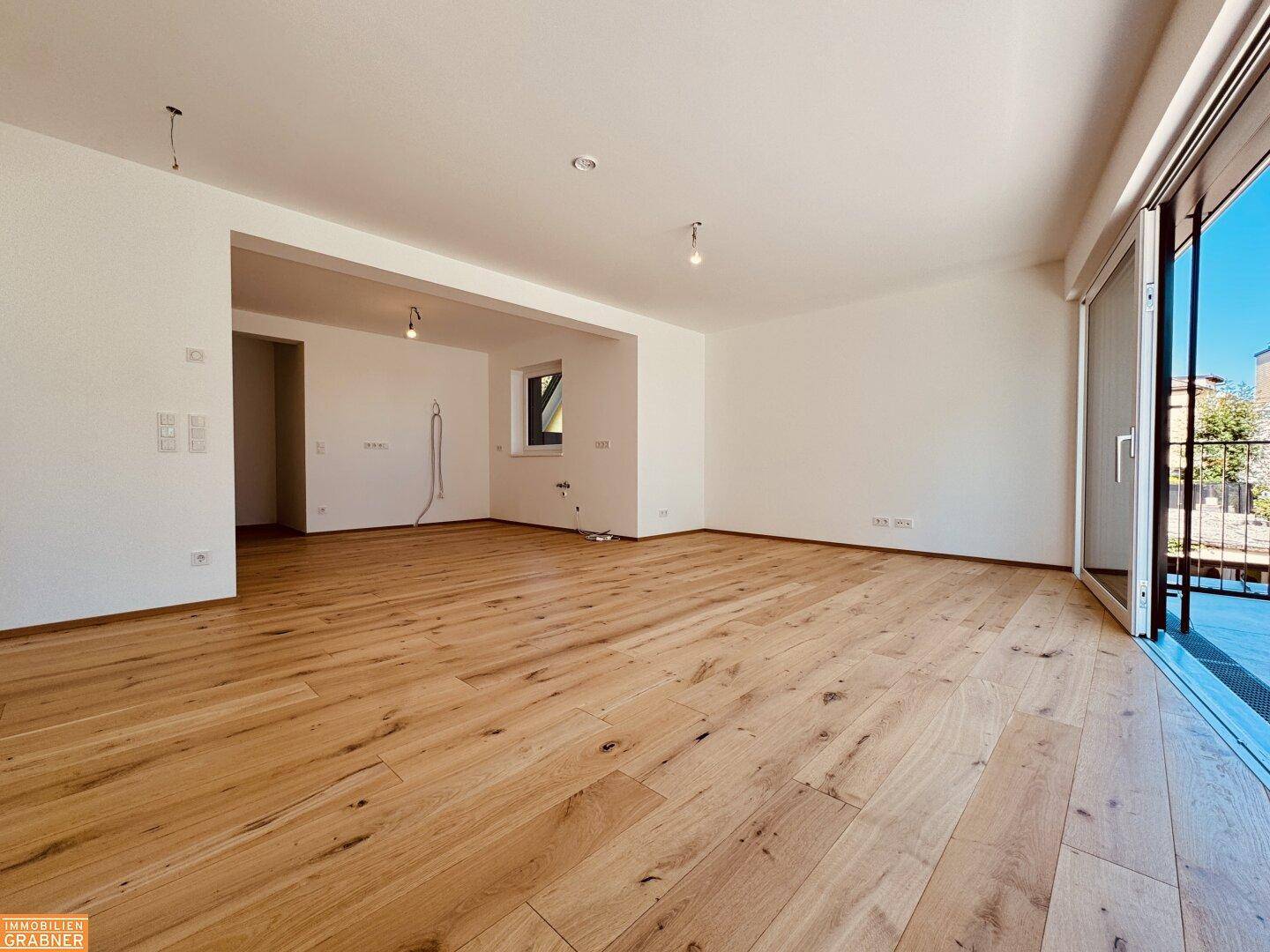 Geräumiges, leeres Wohnzimmer mit Holzboden und viel Tageslicht, bereit zur individuellen Gestaltung.