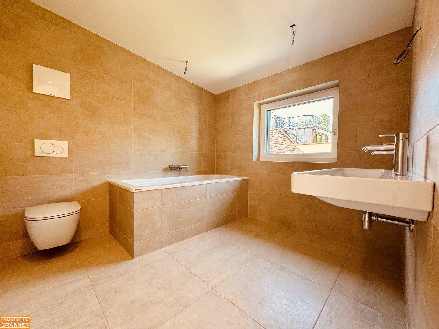 Modernes Badezimmer mit beigefarbenen Fliesen, Badewanne, wandhängendem WC und Fenster.