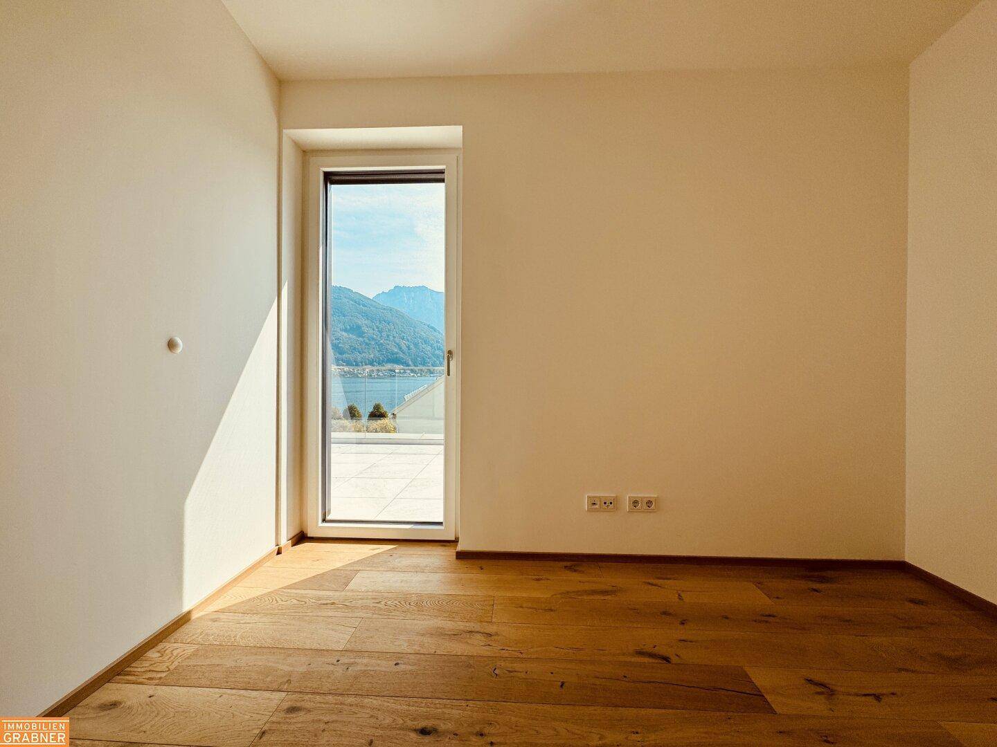Sonniges Zimmer mit Holzboden und direktem Zugang zur Terrasse mit wunderschönem Seeblick.