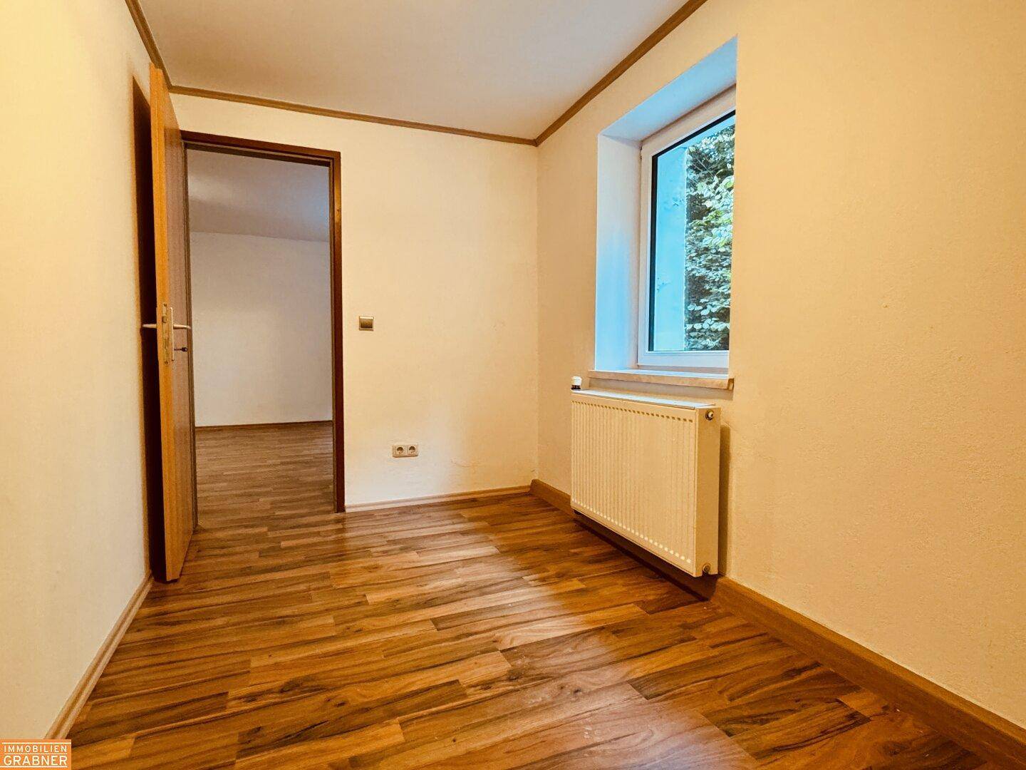 Kleineres Zimmer mit Holzboden und Fenster, ideal als Kinderzimmer oder Büro nutzbar.