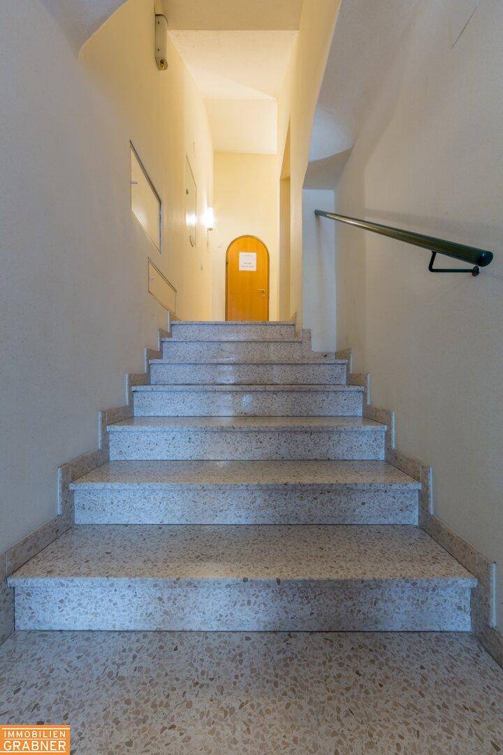 Helles Treppenhaus mit Steinstufen und schlichtem Geländer.