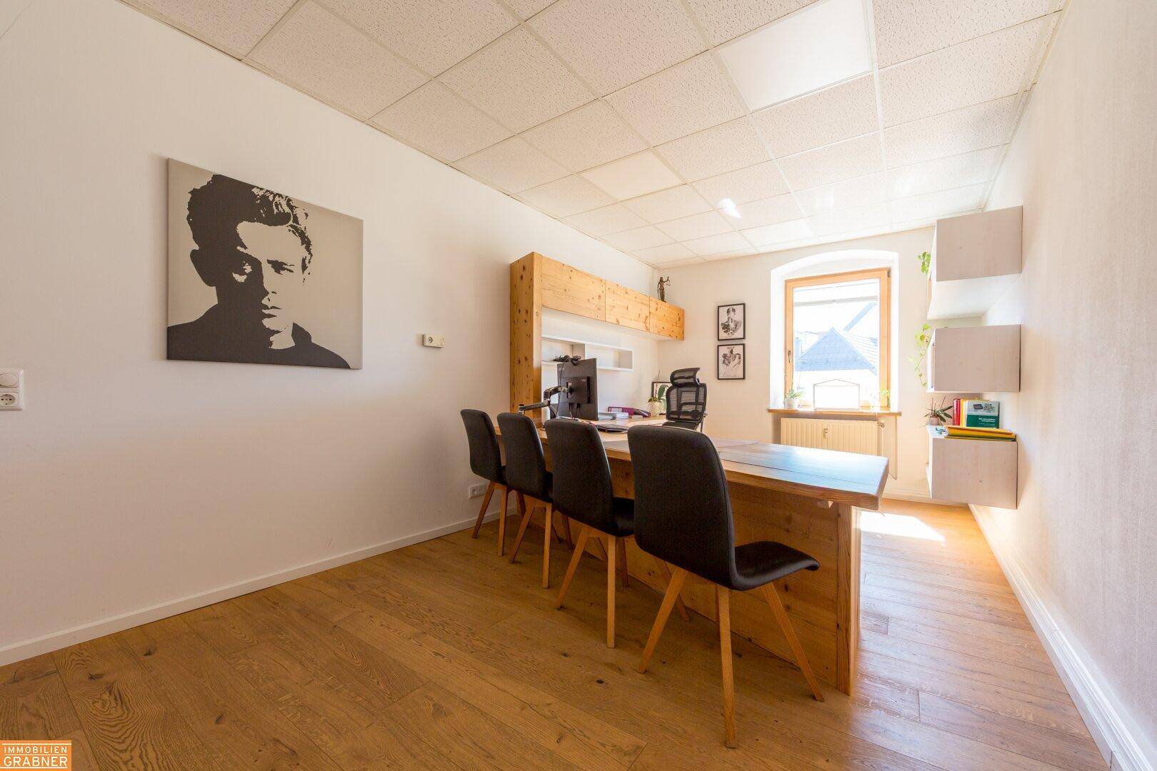 Geräumiges Büro mit Holzboden, großem Schreibtisch und modernem Wandbild.