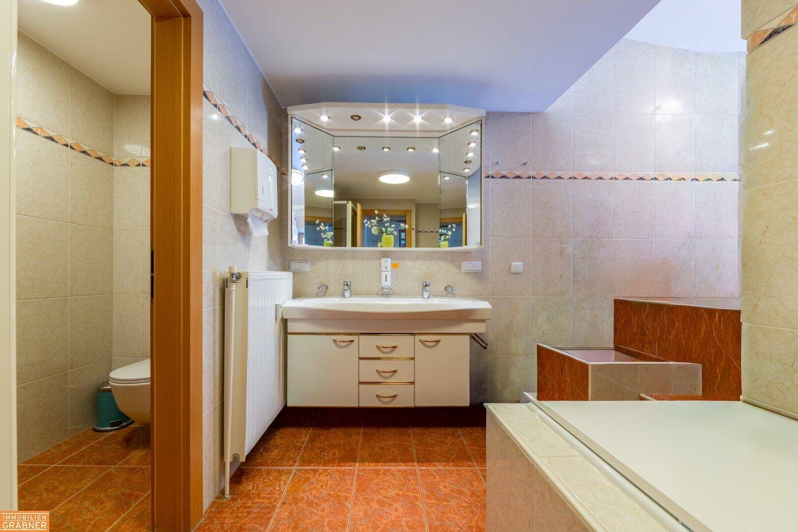 Geräumiges Badezimmer mit Doppelwaschbecken, Badewanne und gefliestem Boden.