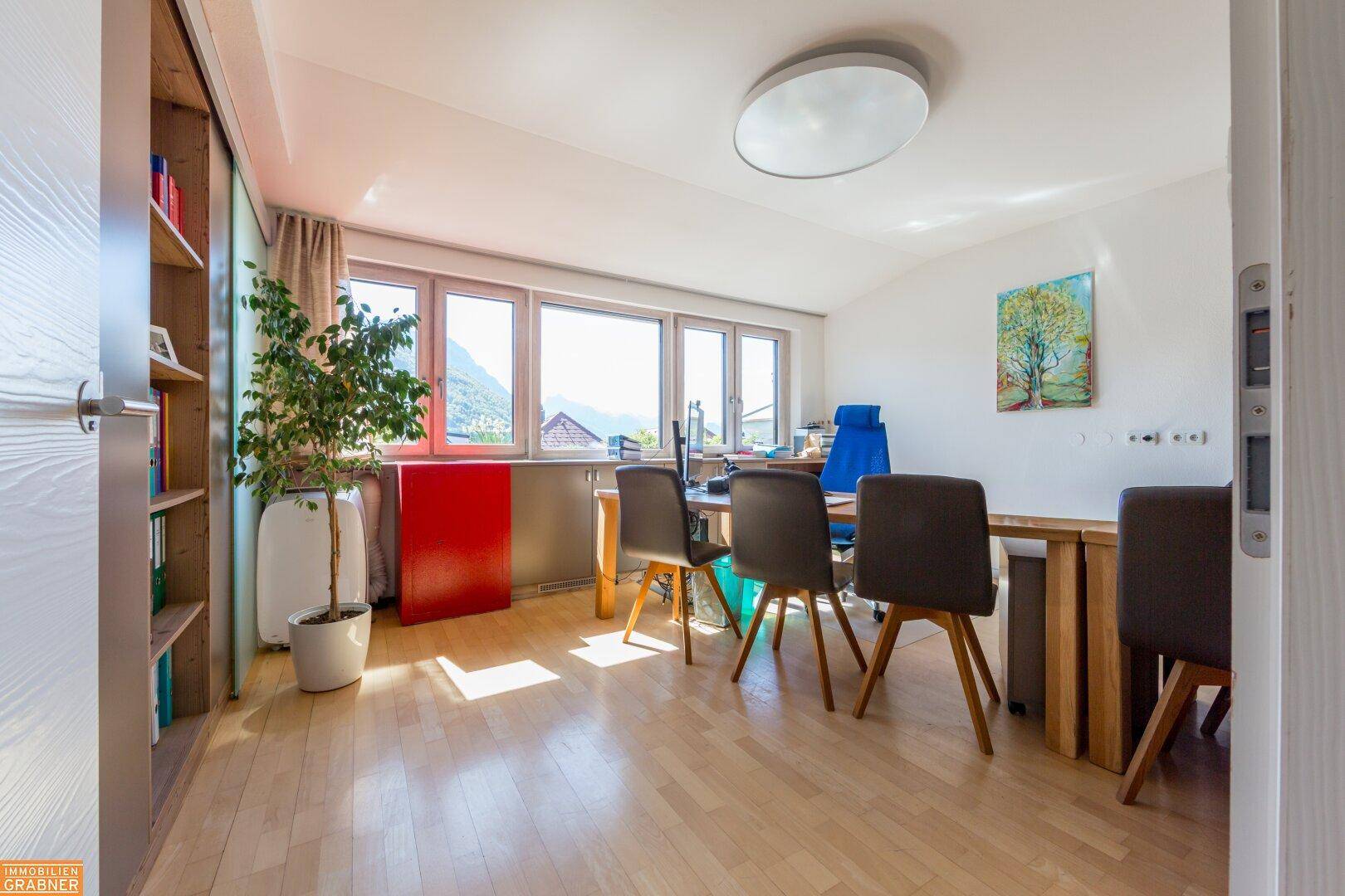 Helles Büro mit Holzboden, großen Fenstern und malerischem Bergblick.