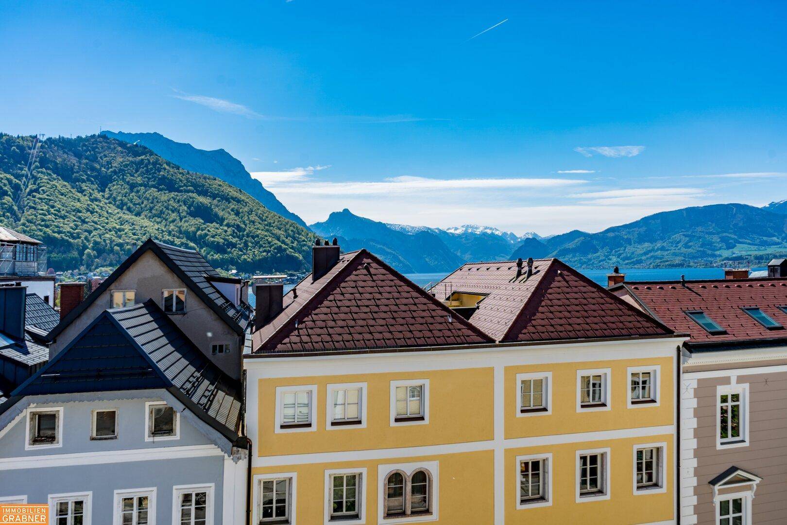 Panoramablick über die Dächer der Stadt mit See- und Bergsicht in der Ferne.