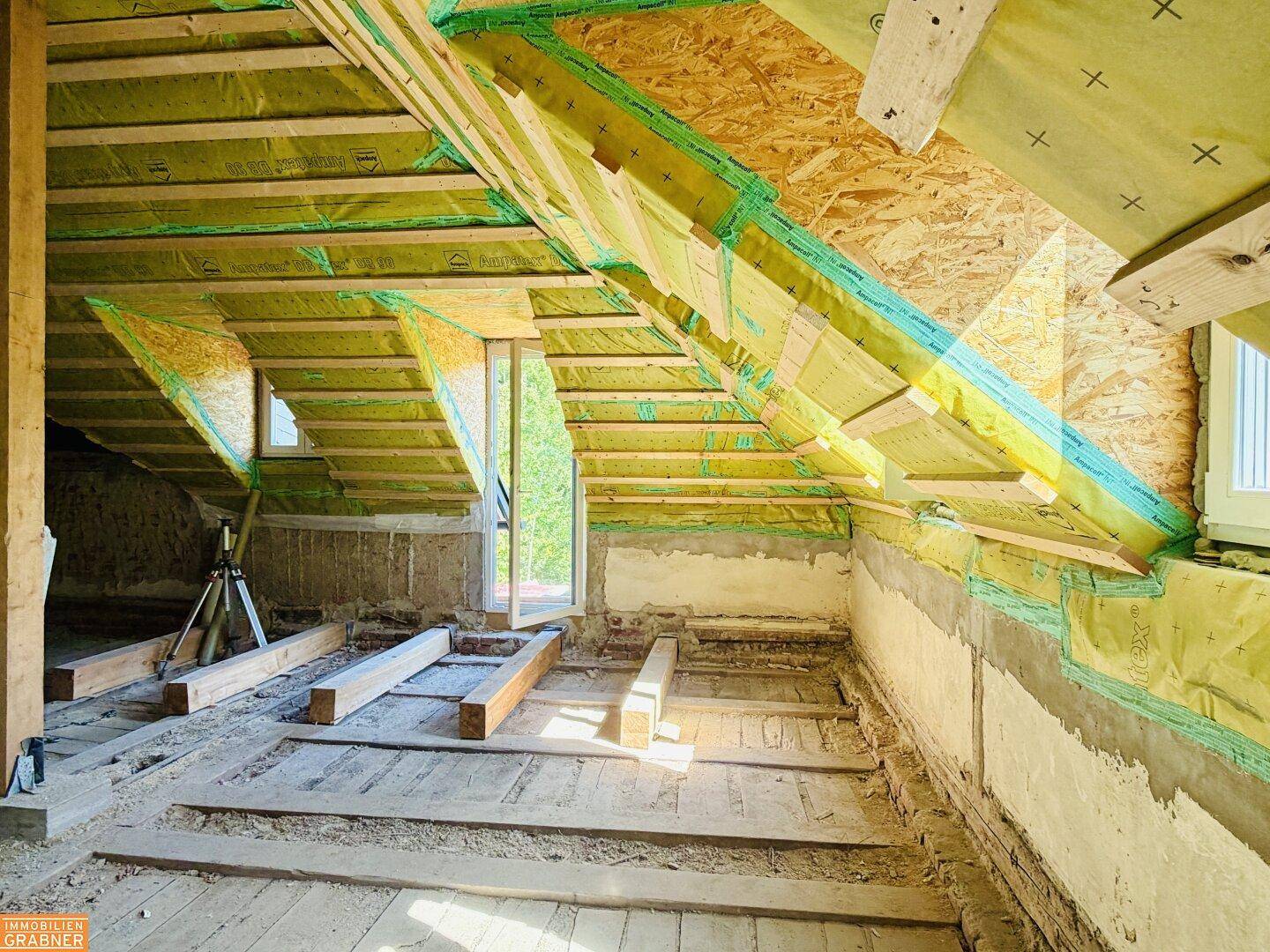 Dachgeschoss im Rohbau mit sichtbarer Dachkonstruktion, Dämmung und Holzelementen.