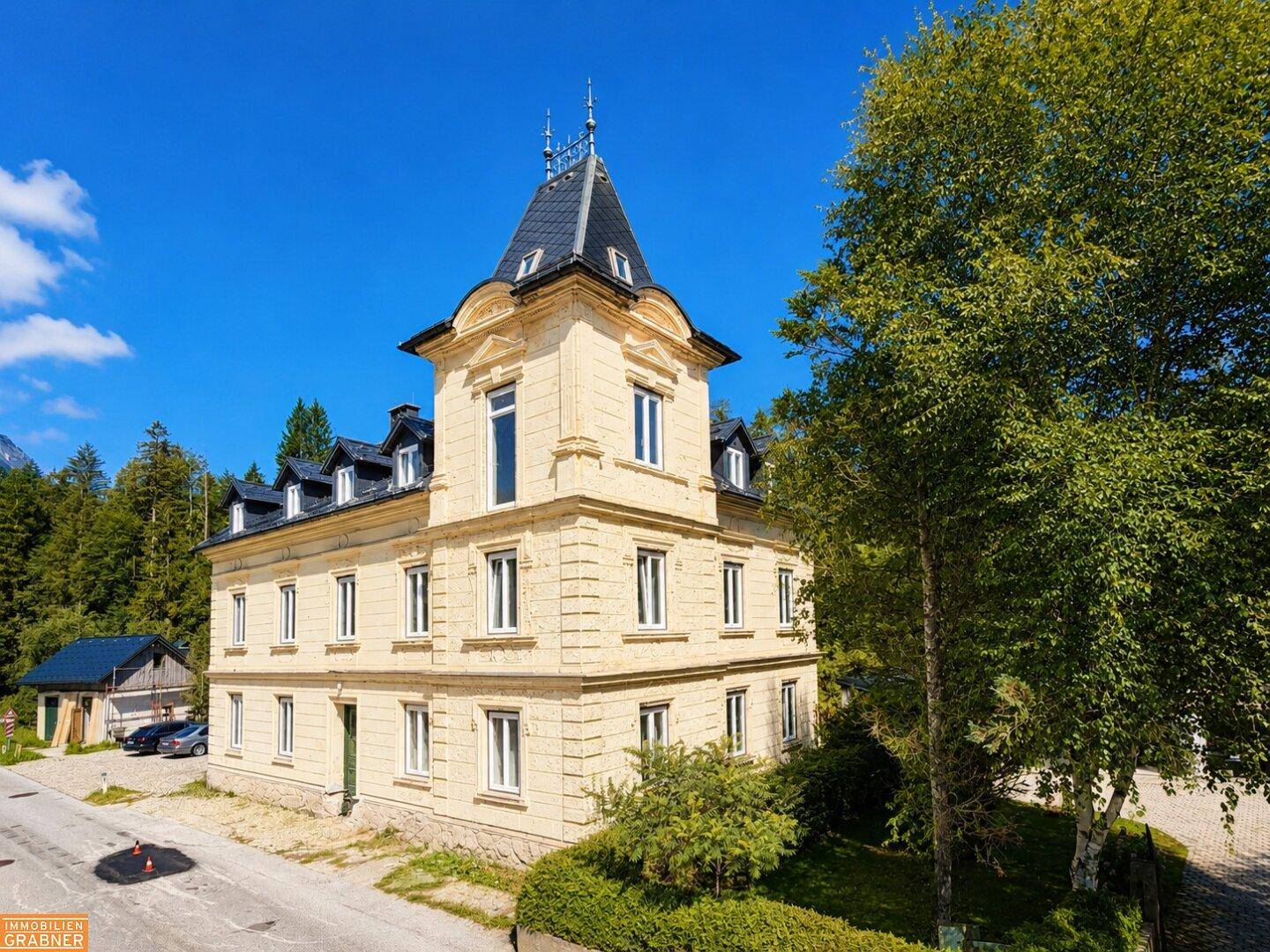 Historisches Gebäude mit markantem Turm und klassischer Architektur unter blauem Himmel.