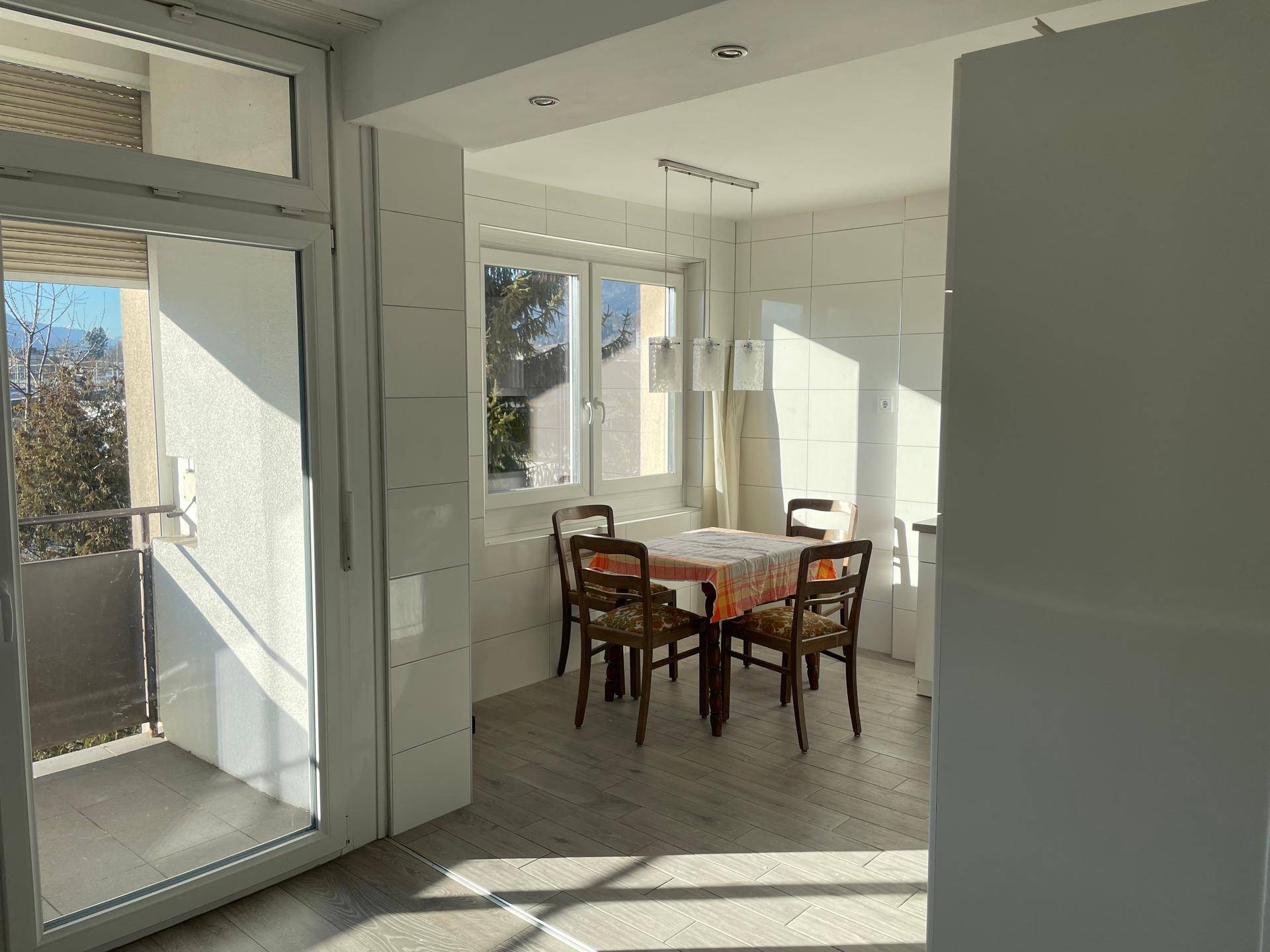 Heller Essbereich neben der Küche mit Esstisch, Stühlen und Zugang zum Balkon.