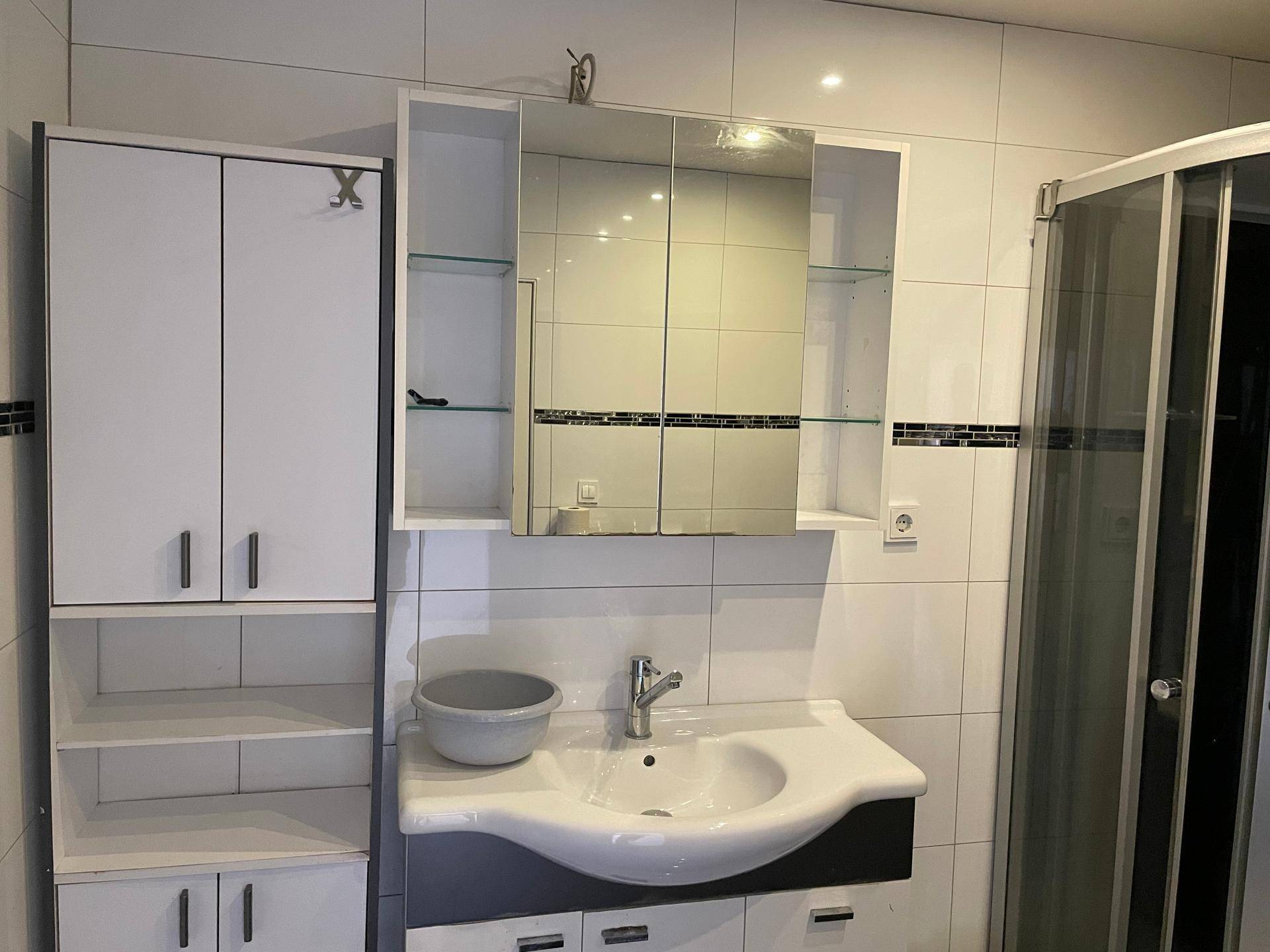 Waschtischbereich im Badezimmer mit Spiegelschrank, Unterschrank und praktischen Ablagen.