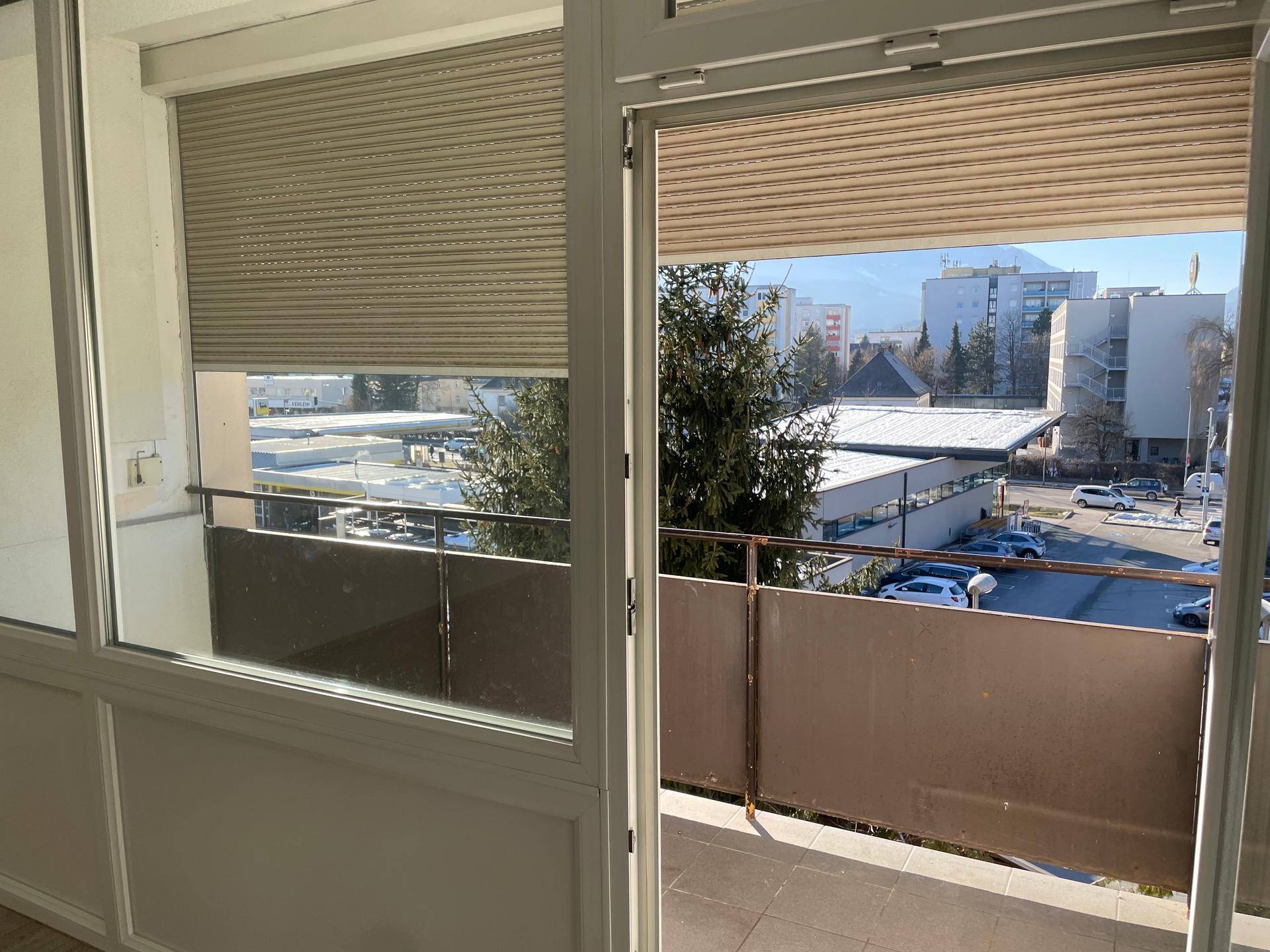 Blick vom Balkon auf die umliegende Stadtlandschaft mit Gebäuden und Parkplätzen.