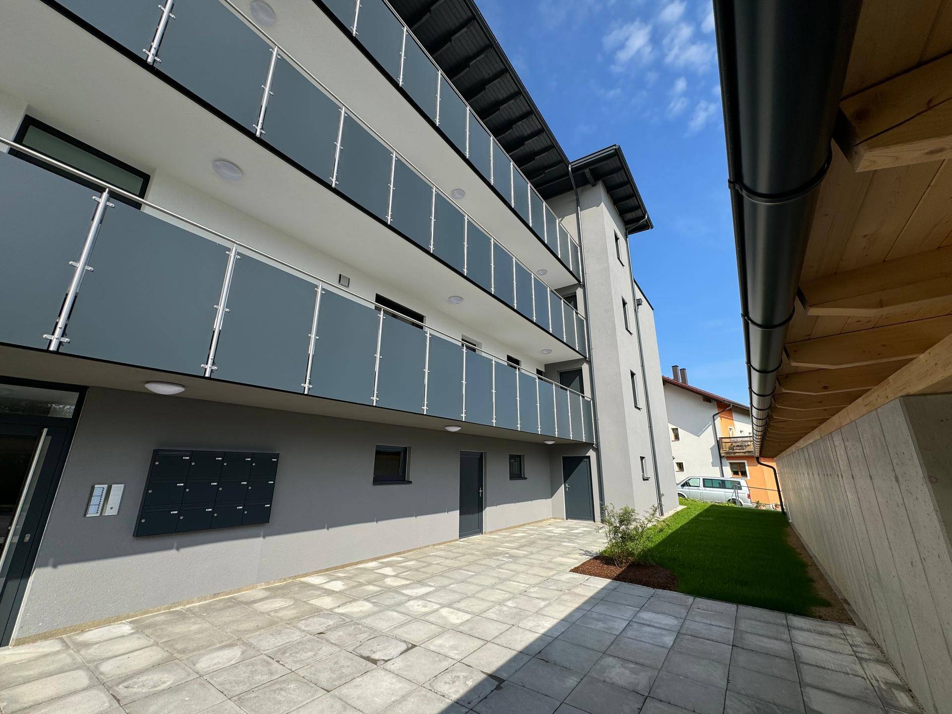 Gepflasterter Außenbereich am Eingang des Gebäudes mit Blick auf die Carport-Konstruktion.
