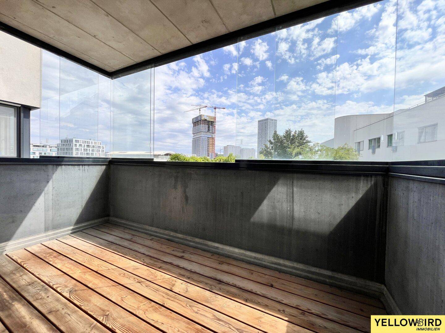 Verglaste Loggia mit Holzboden und Blick auf die Stadt und umliegende Gebäude.