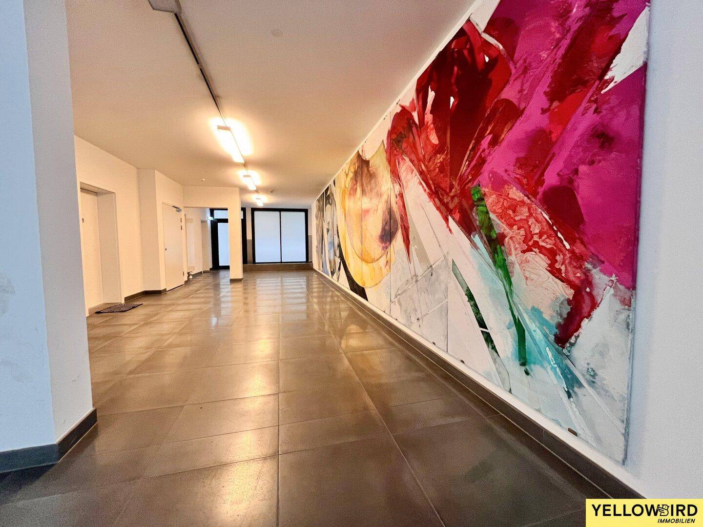 Moderner Flur mit großformatigen Fliesen und einem farbenfrohen Kunstwerk an der Wand.