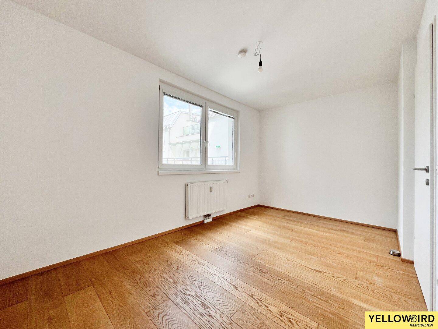 Helles Zimmer mit Parkettboden und Fenster, ideal als Schlaf- oder Arbeitszimmer nutzbar.