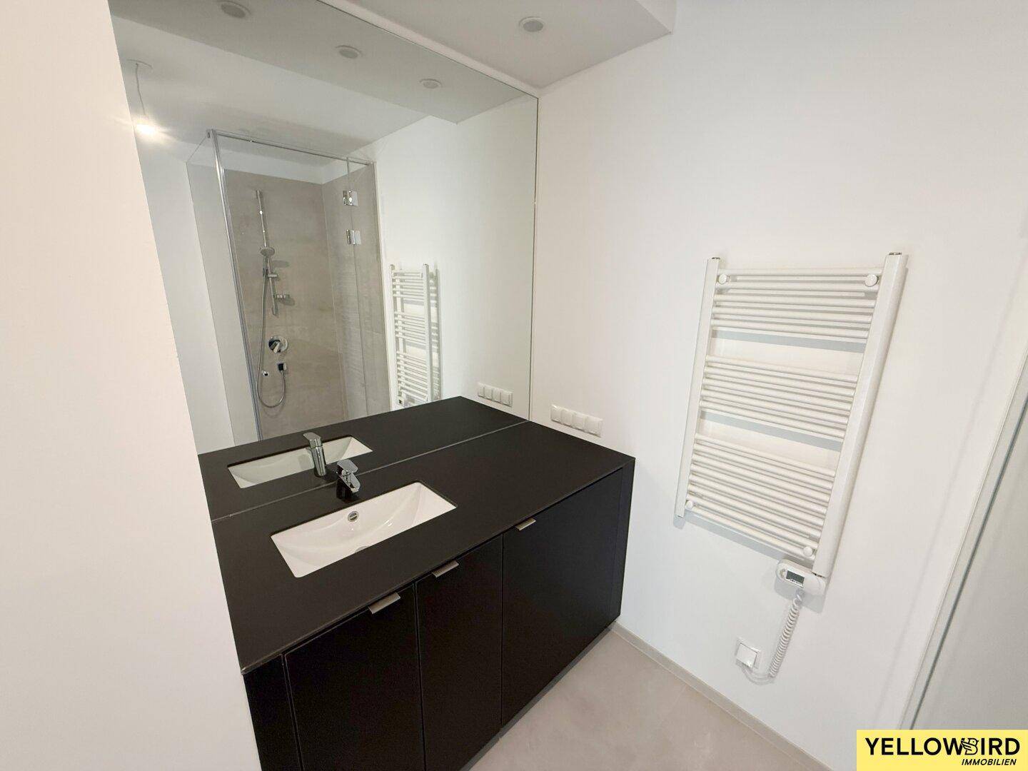 Modernes Badezimmer mit schwarzem Waschtischunterschrank, großem Spiegel und Handtuchheizkörper.