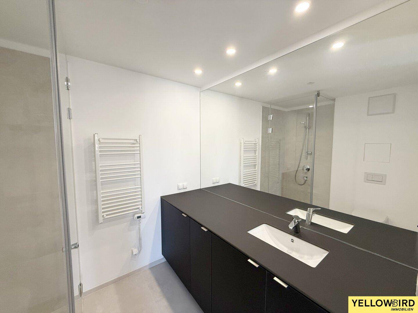 Modernes Badezimmer mit großem Spiegel, Einzelwaschbecken und beheiztem Handtuchhalter, in elegantem Design.